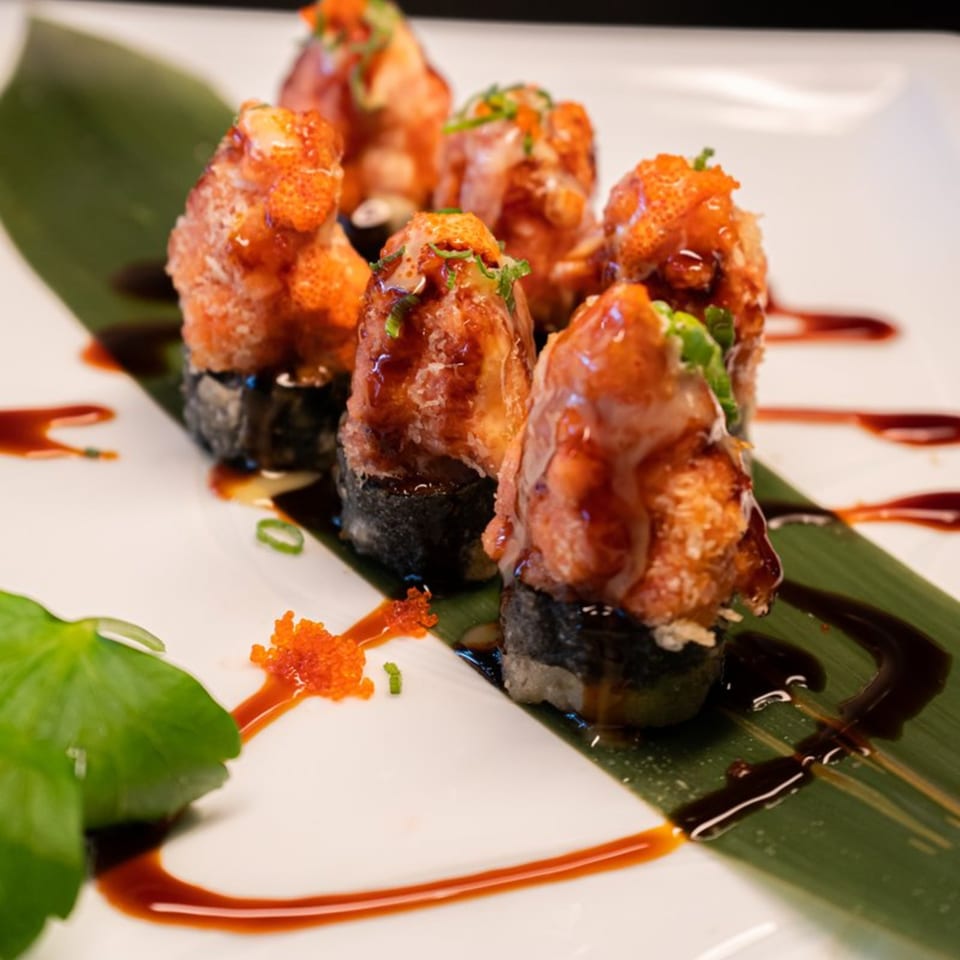 Six pieces of Modern Fusion's baked sushi rolls, drizzled with sauce and garnished with roe and chives.