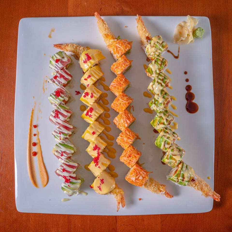 Four rows of colorful Modern Fusion sushi rolls with various toppings and sauces on a white plate.