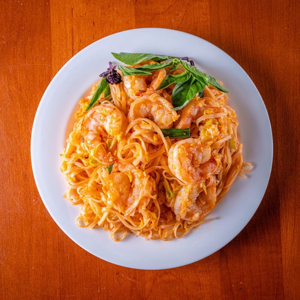 Modern Fusion's shrimp Pad Thai with noodles, bean sprouts, and fresh basil on a white plate.